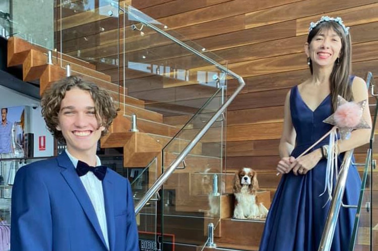 Darlene Chin from Darwin, dressed in a blue ball gown standing with a teenage boy dressed in a suit on a stairwell.