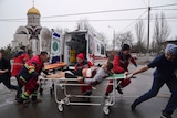 Paramedics move an injured man on a stretcher.