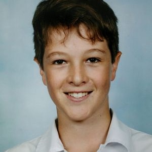A school photo of a smiling young fellow with dark hair and brown eyes.