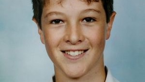 A school photo of a smiling young fellow with dark hair and brown eyes.