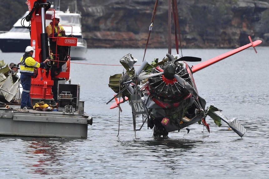 NSW Police and salvage personnel lift the body of the wreckage of a seaplane
