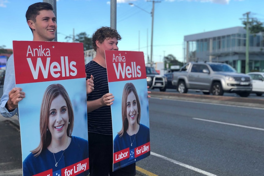 Supporters hold placards of of Anika Wells in the seat of Lilley.