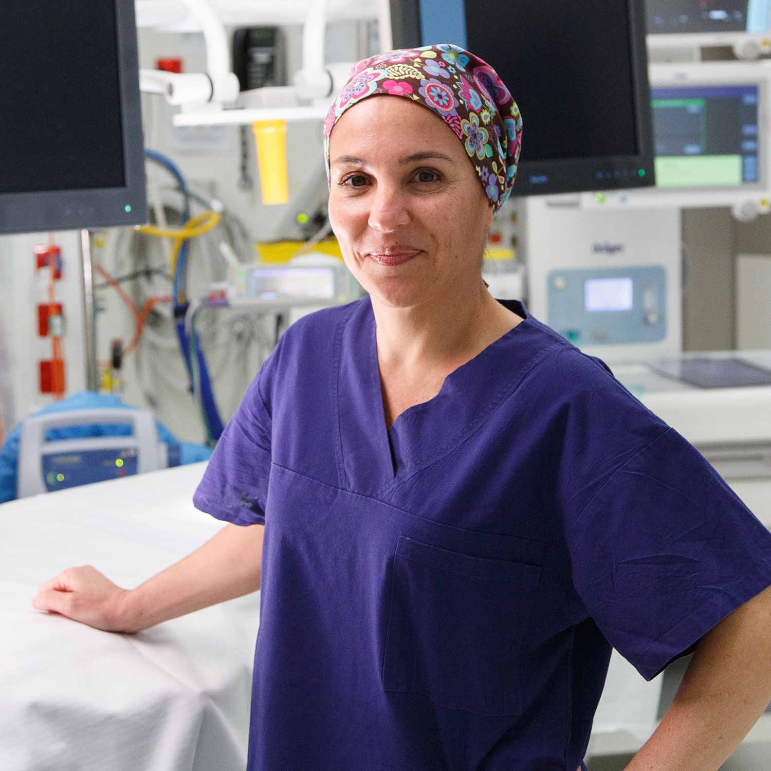 Woman wearing navy surgery scrubs and hat smiling
