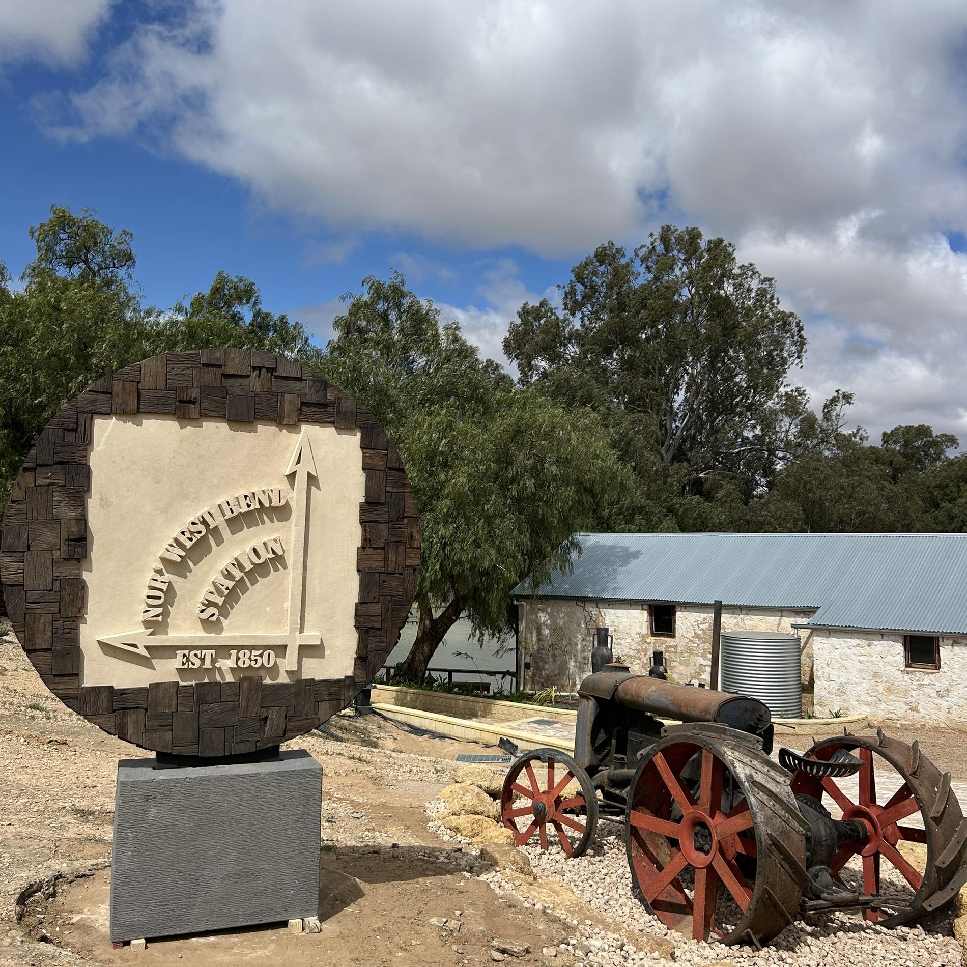 Un letrero dice Estación Nor' West Bend con un tractor viejo y un edificio al fondo.