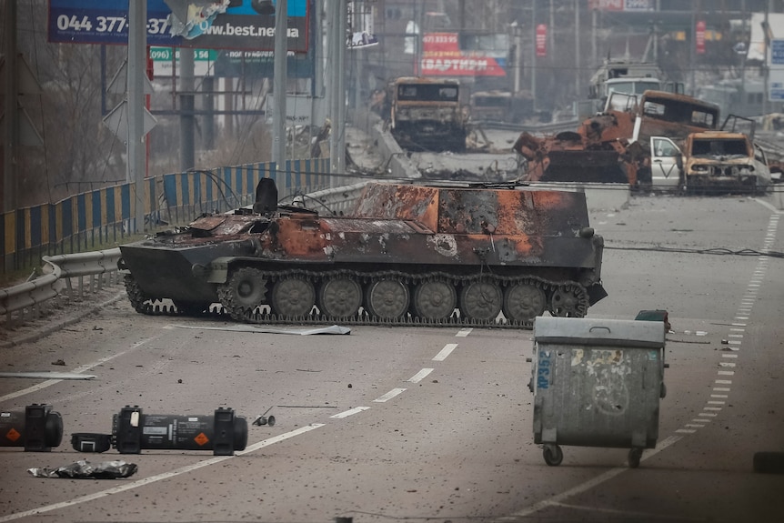 Wrecked tanks on a bridge, surrounded by trash 