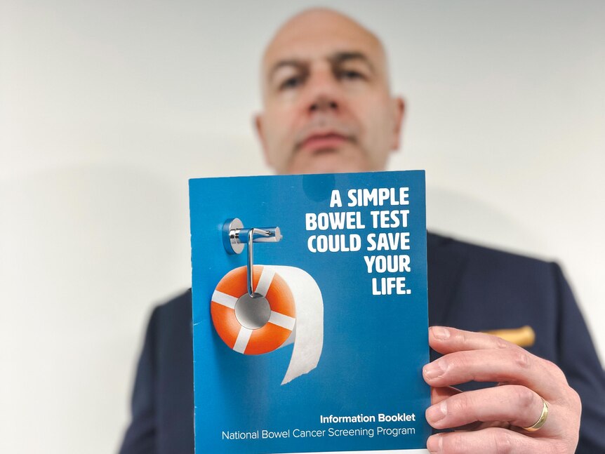 A man holds up a brochure saying: "A simple bowel test could save your life."