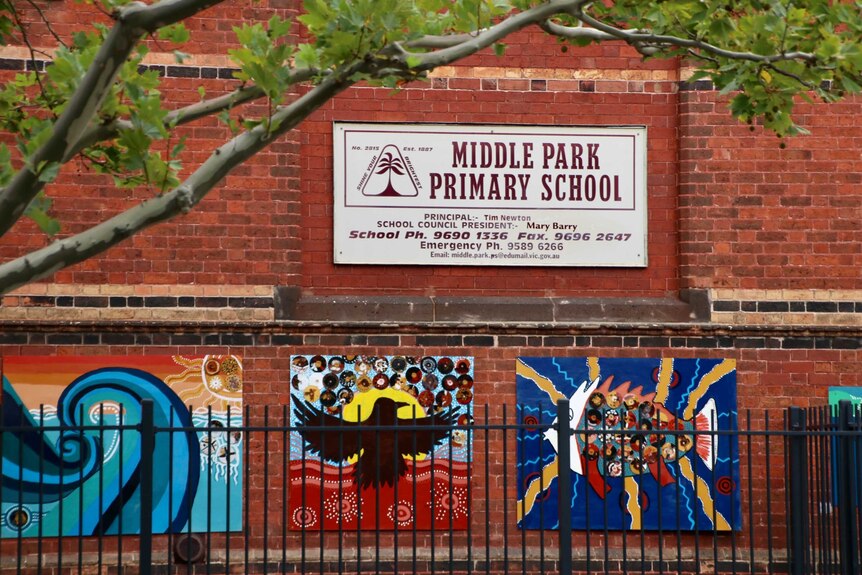The exterior of Middle Park Primary School, which has a sign and paintings on a brick wall.