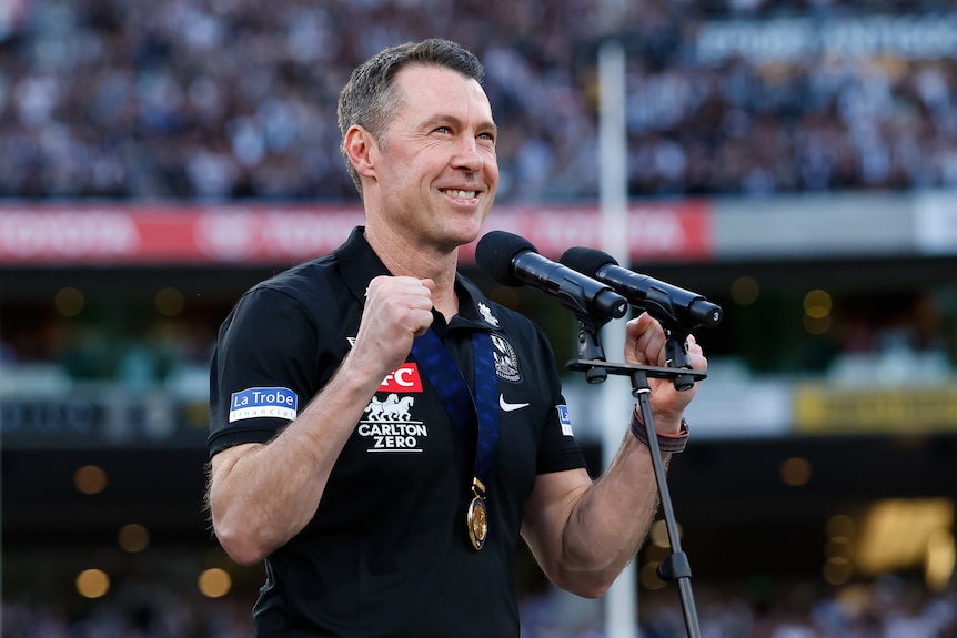 Craig McRae wears a medal and smiles