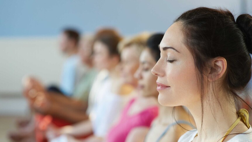 Profile of woman meditating with eyes closed, in group class