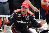 Will Power, sitting on his car, clenches his fists in celebration.