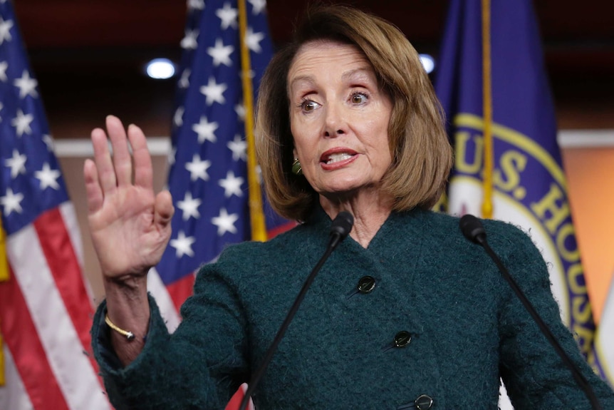 Nancy Pelosi holds her hand up at a press conference