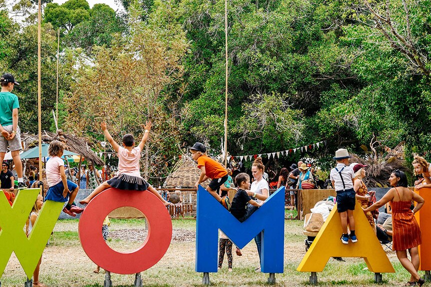 The word WOMAD is spelt out in letters being climbed over by children
