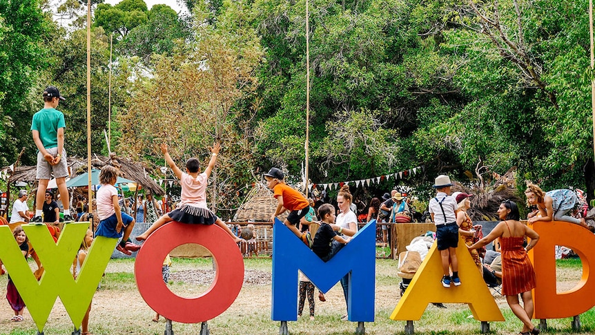 The word WOMAD is spelt out in letters being climbed over by children