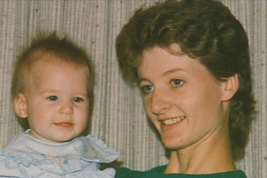 An old photo of a young woman holding a smiling baby.