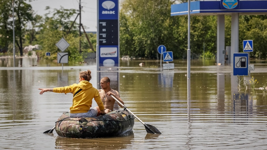Local residents sail on a boat at a street during an evacuation from a flooded area in Ukraine.