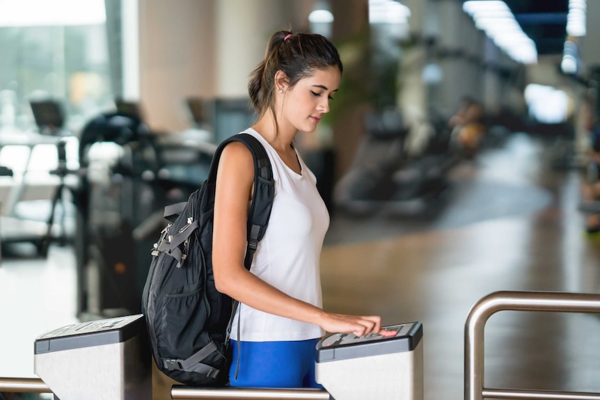 A woman scanning her fingerprint to access the gym