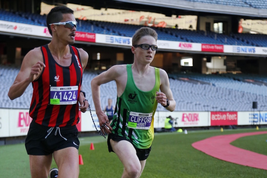 Matthew Clarke runs next to Jaryd Clifford, joined by a tether, as he helps guide the visually-impaired runner in a race.