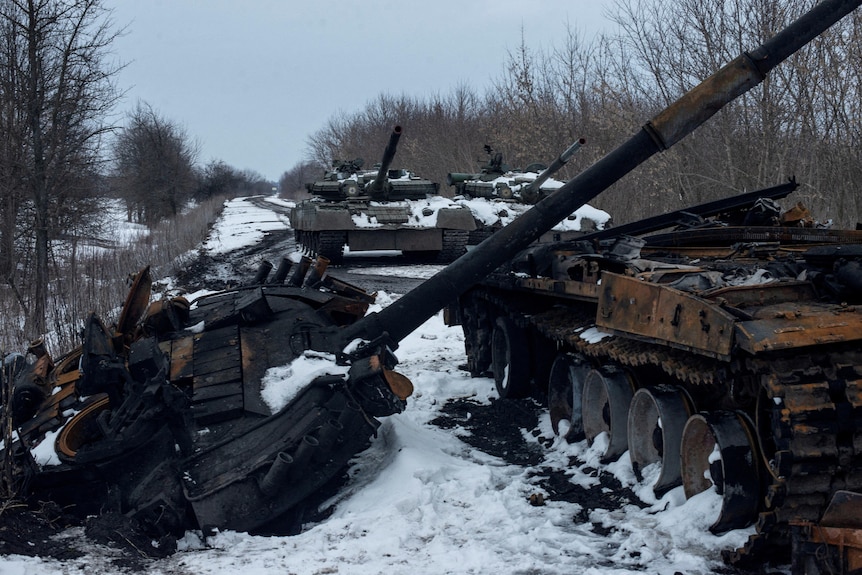 The charred remains of one tank sit in the snow beside two other tanks that remain intact