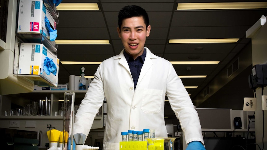 Dr Candrawinata leans on a lab bench.