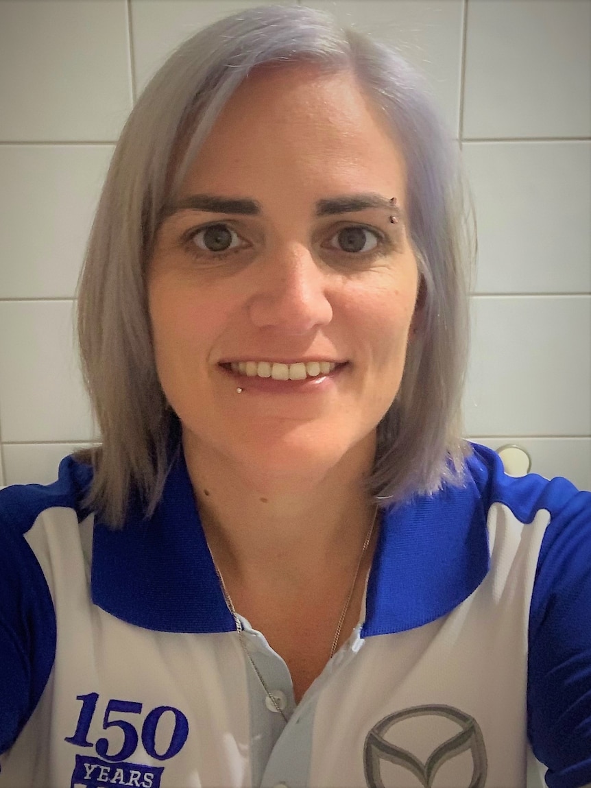Selfie of woman in collared sports shirt against tiled background.