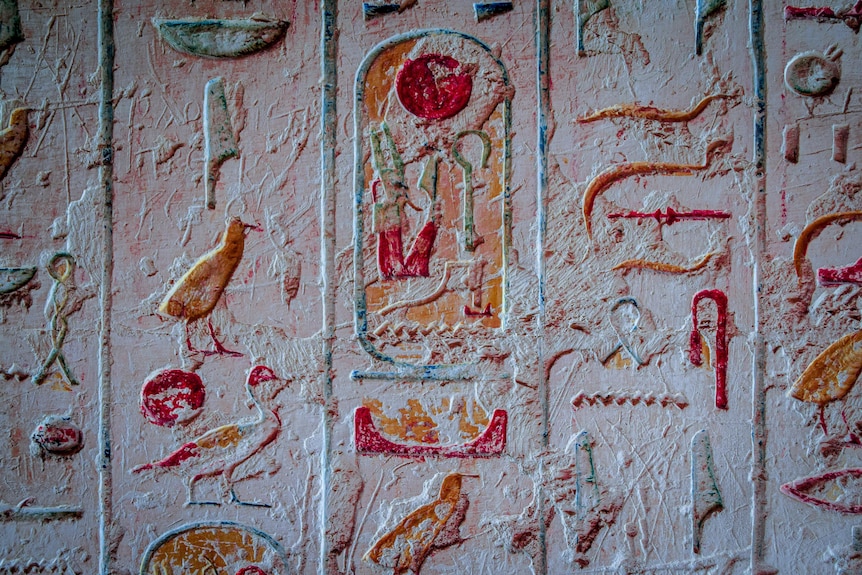 Very old-looking coloured inscriptions in stone of symbols and different kinds of birds.