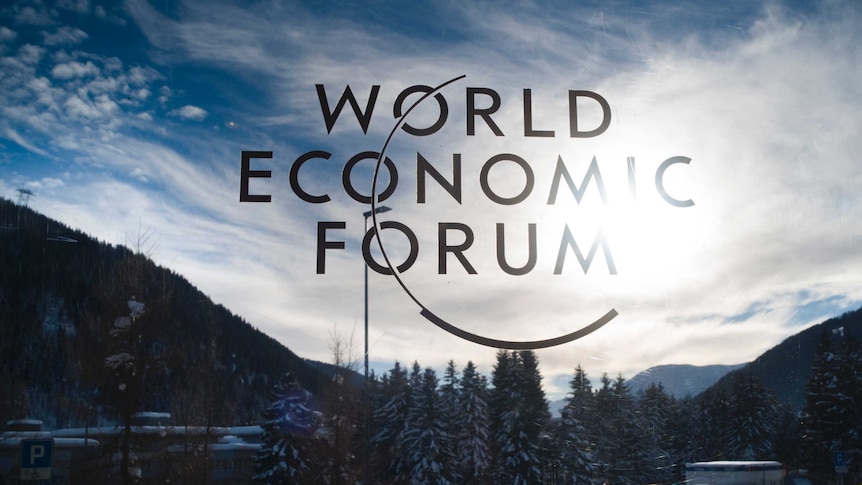 The sign of the World Economic Forum at an entrance at davos in Switzerland with snow in the background.