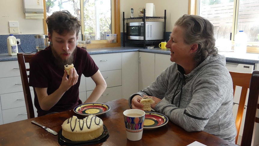 Angela Wilton and her 21-year-old son sitting at a kitchen table eating cake.