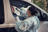 A female driver has a coronavirus test swab put into her mouth.