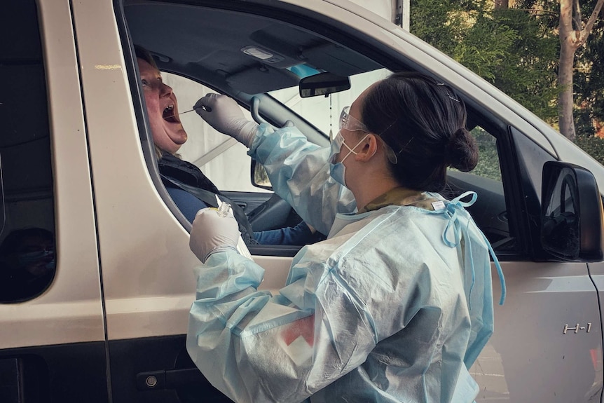 A female driver has a coronavirus test swab put into her mouth.