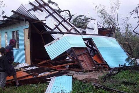 A house lay in ruins with sheets of tin and iron twisted on the ground.