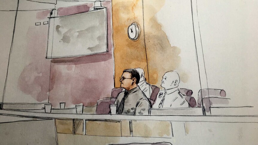 Sketch of a bespectacled man sitting in the dock of a court with two guards behind him.