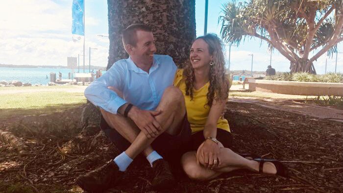 Nicki Jeffery sitting with her husband under a tree in Port Macquarie