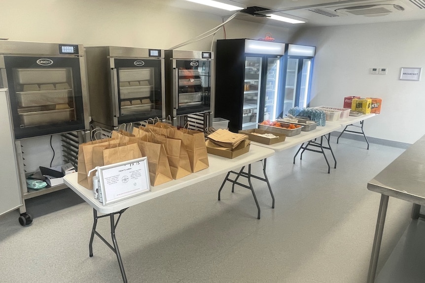 A long table laden with meals packaged in carry bags.