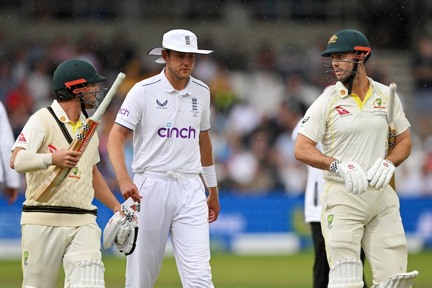 Australia batters Travis Head and Mitch Marsh walk off Headingley on either side of England bowler Stuart Broad in the rain.