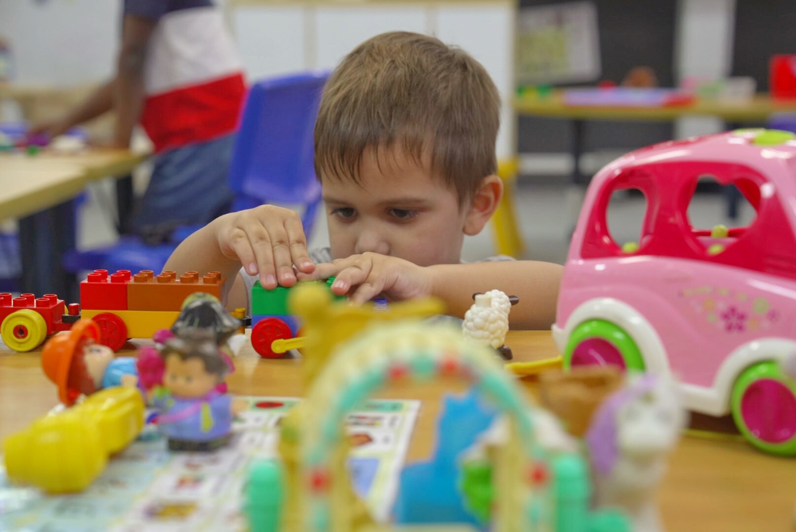 A young boy focusing on the toy blocks he's playing with.