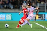 A Japanese striker sidefoots the ball towards goal as she runs alongside a Norway defender.