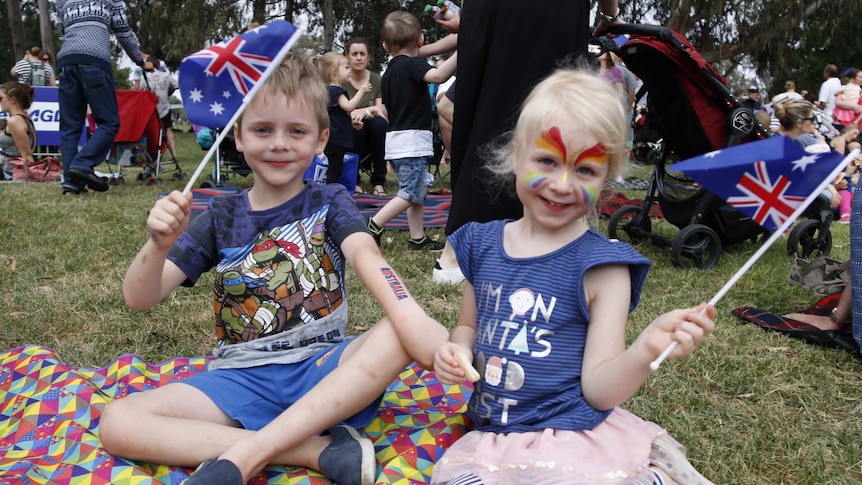 Two children wave flags at Australia Day Breakfast in Canberra.