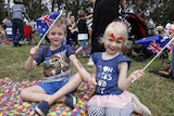 Two children wave flags at Australia Day Breakfast in Canberra.