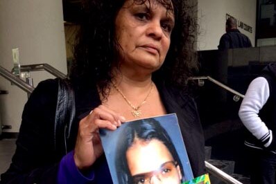 Kriss Derschow holds photos of her murdered daughter Shionah Carter outside an inquest into her death