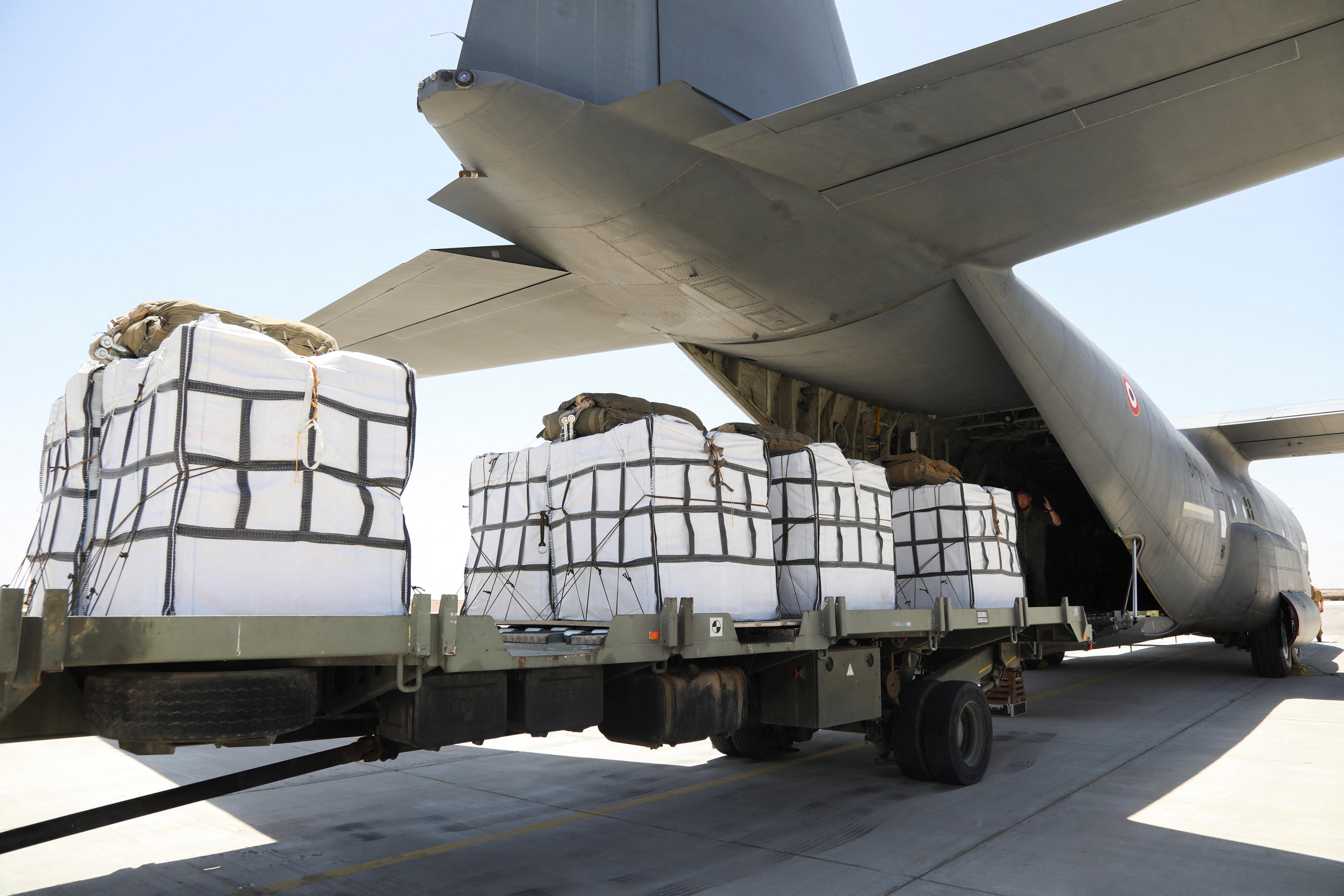 Pallets of aid being loaded into the back of a large military plane.