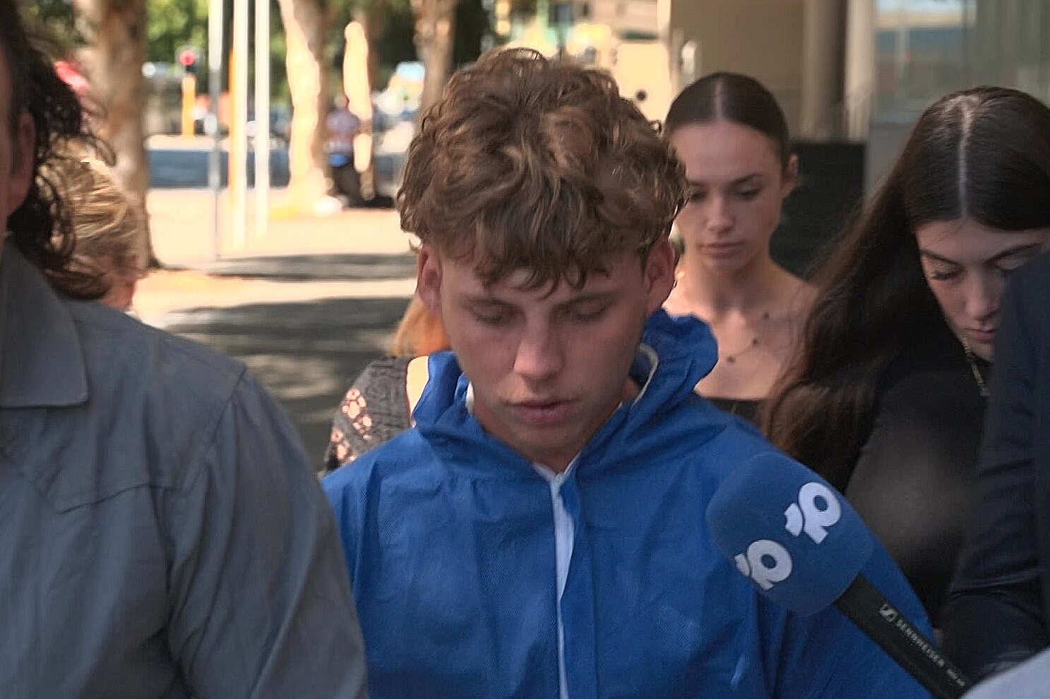 A man in a tracksuit walks amongst a group of other people down a footpath