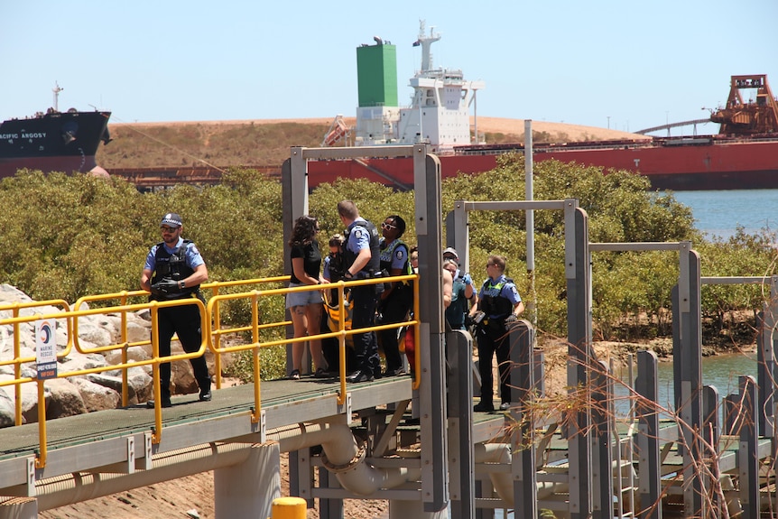 A nam is carried up a pier by a group of police and civilians.