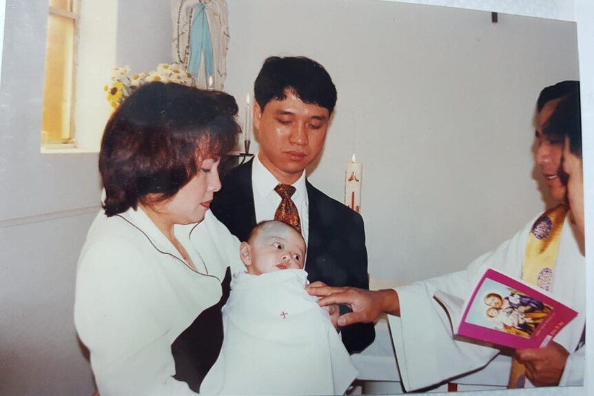 Photo of Peter Nguyen, as a baby, being held by his parents and baptised by a Catholic Vietnamese priest. 