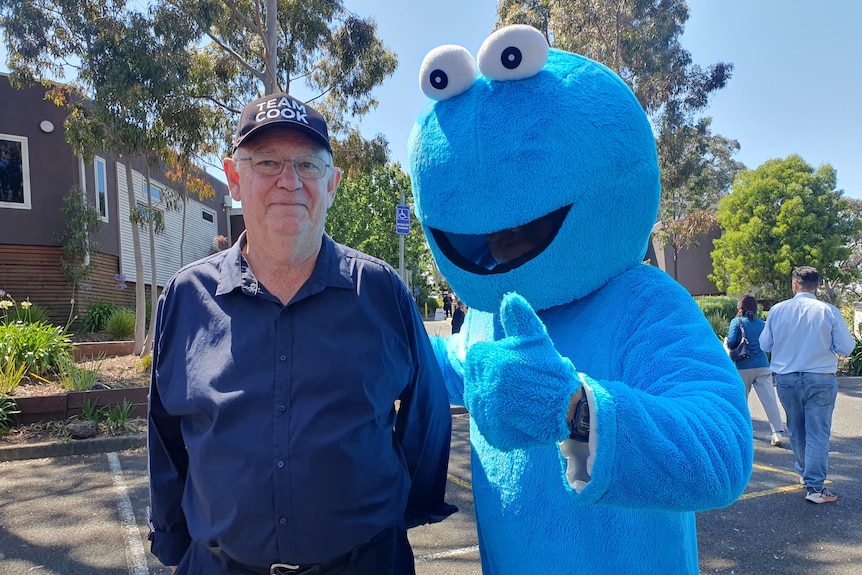 Man in dark blue shirt, wearing 'team cook' hat, and a life-sized 'cookie monster'
