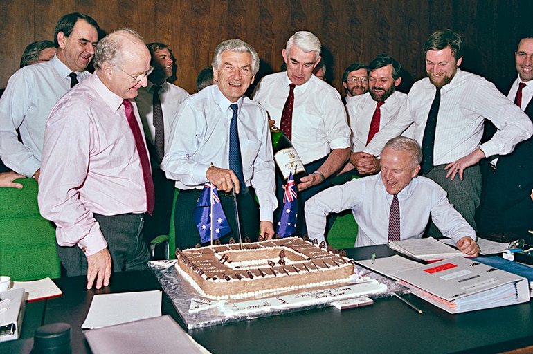 Bob Hawke, surrounded by other ministers and staff, cuts a cake at the last cabinet meeting in the Old Cabinet Room in 1988.