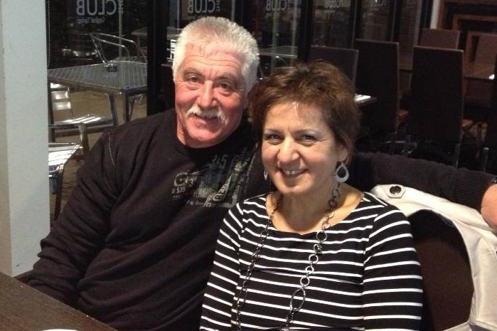 Leo Biancofiore is pictured with his arm around his wife Donna at a dining table in a club, as both smile at the camera.