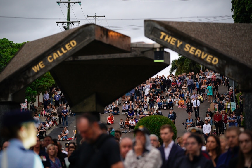 a large group of people stand and sit near a war memorial in Townsville