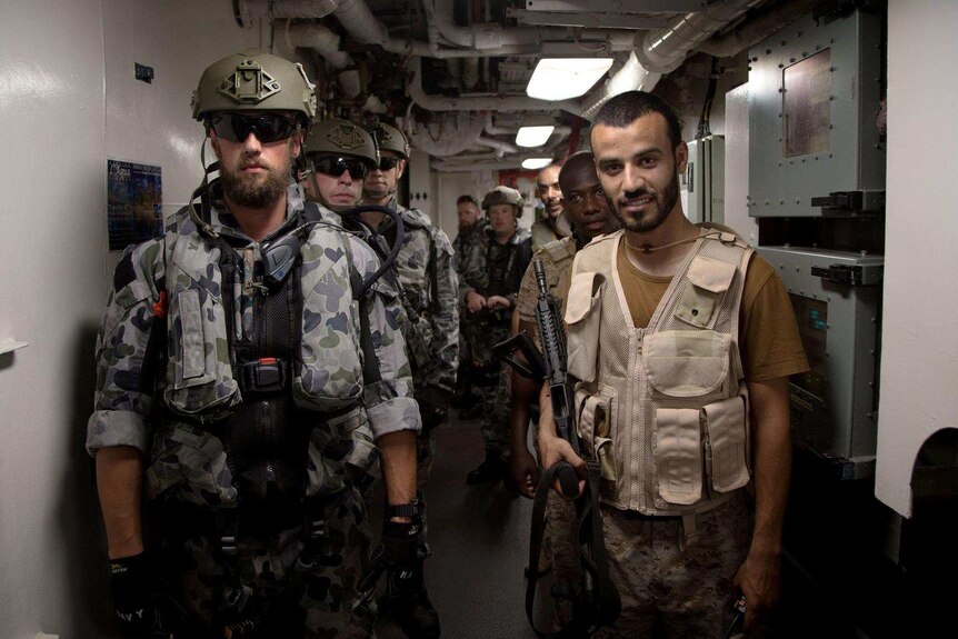 line of Australian Navy sailors  stand alongside a line of Royal Saudi Navy sailors