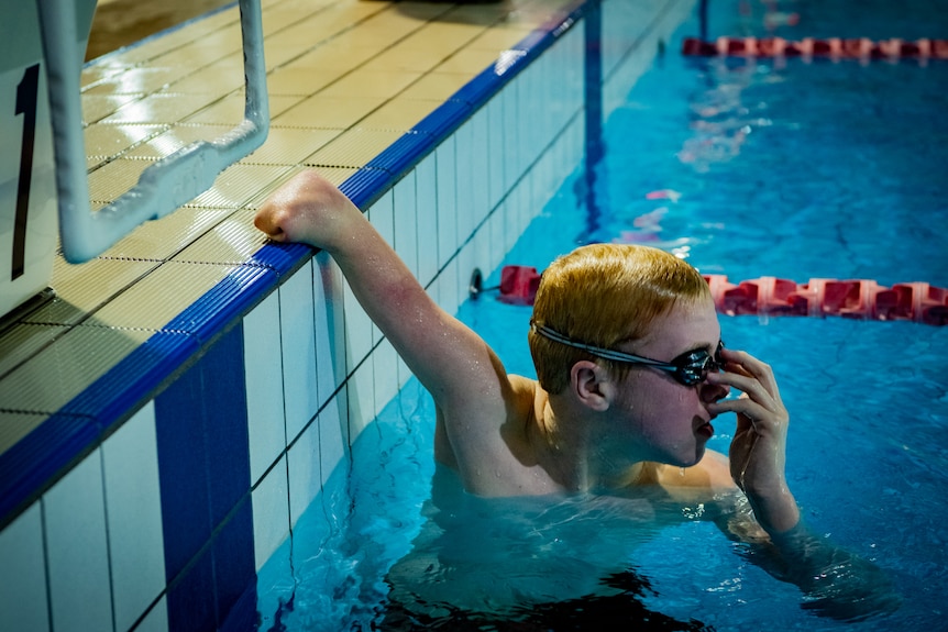 Knox in a lap swimming lame, resting one arm against the side of the pool.