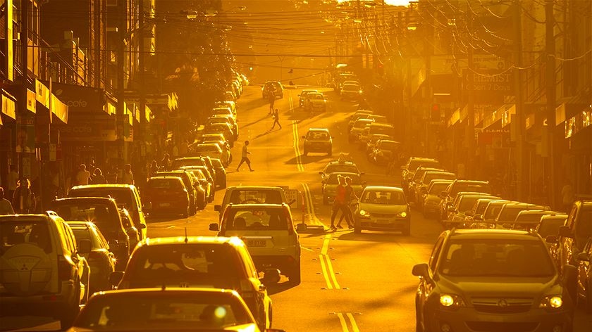 people corssing a busy road during a burning orange sunset